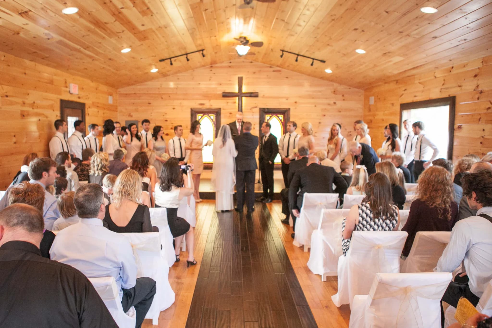 Indoor wedding ceremony in a rustic wood chapel with white chair covers at Moose Hollow Lodge in Pigeon Forge