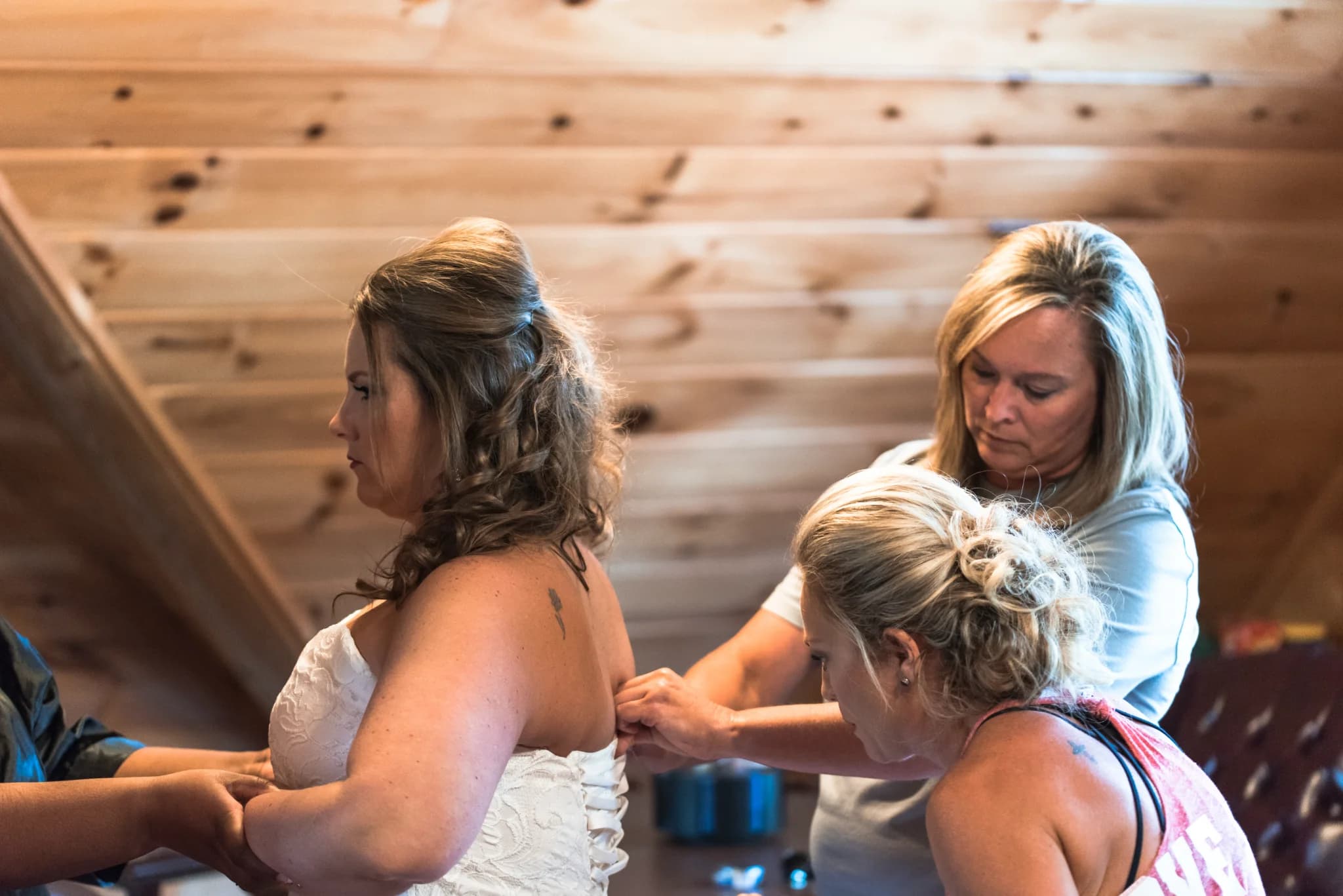 Bride getting into lace wedding dress in a rustic log cabin at Moose Hollow Lodge in Pigeon Forge