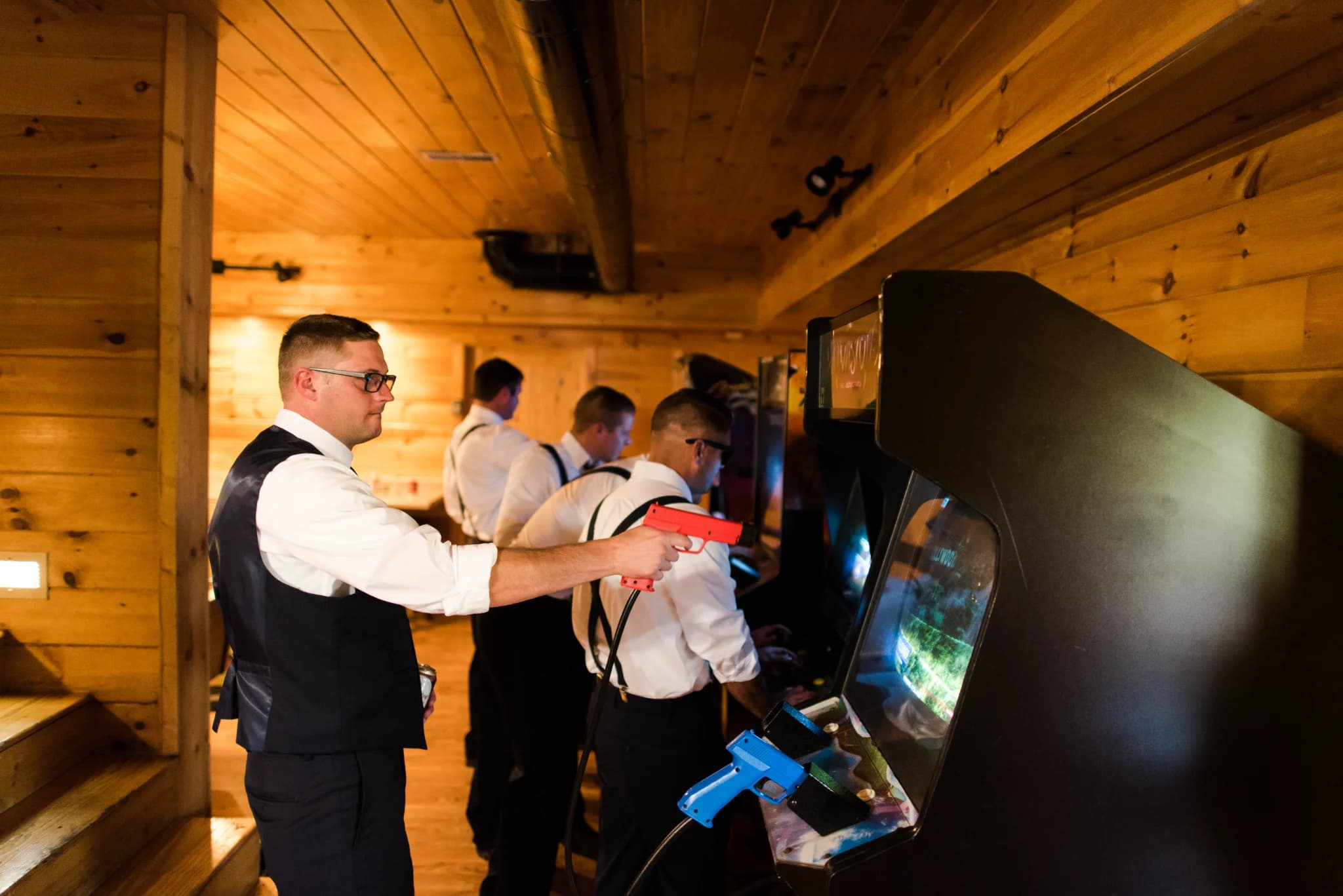 Groomsmen playing arcade games in a wood-paneled game room at Moose Hollow Lodge in Pigeon Forge