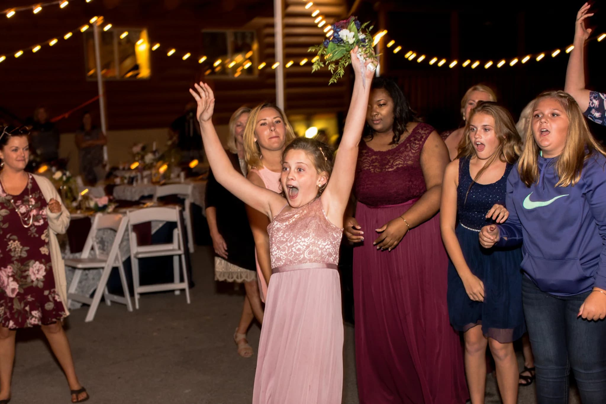 Outdoor wedding bouquet toss under string lights at Moose Hollow Lodge in Pigeon Forge near Dollywood and Smoky Mountains