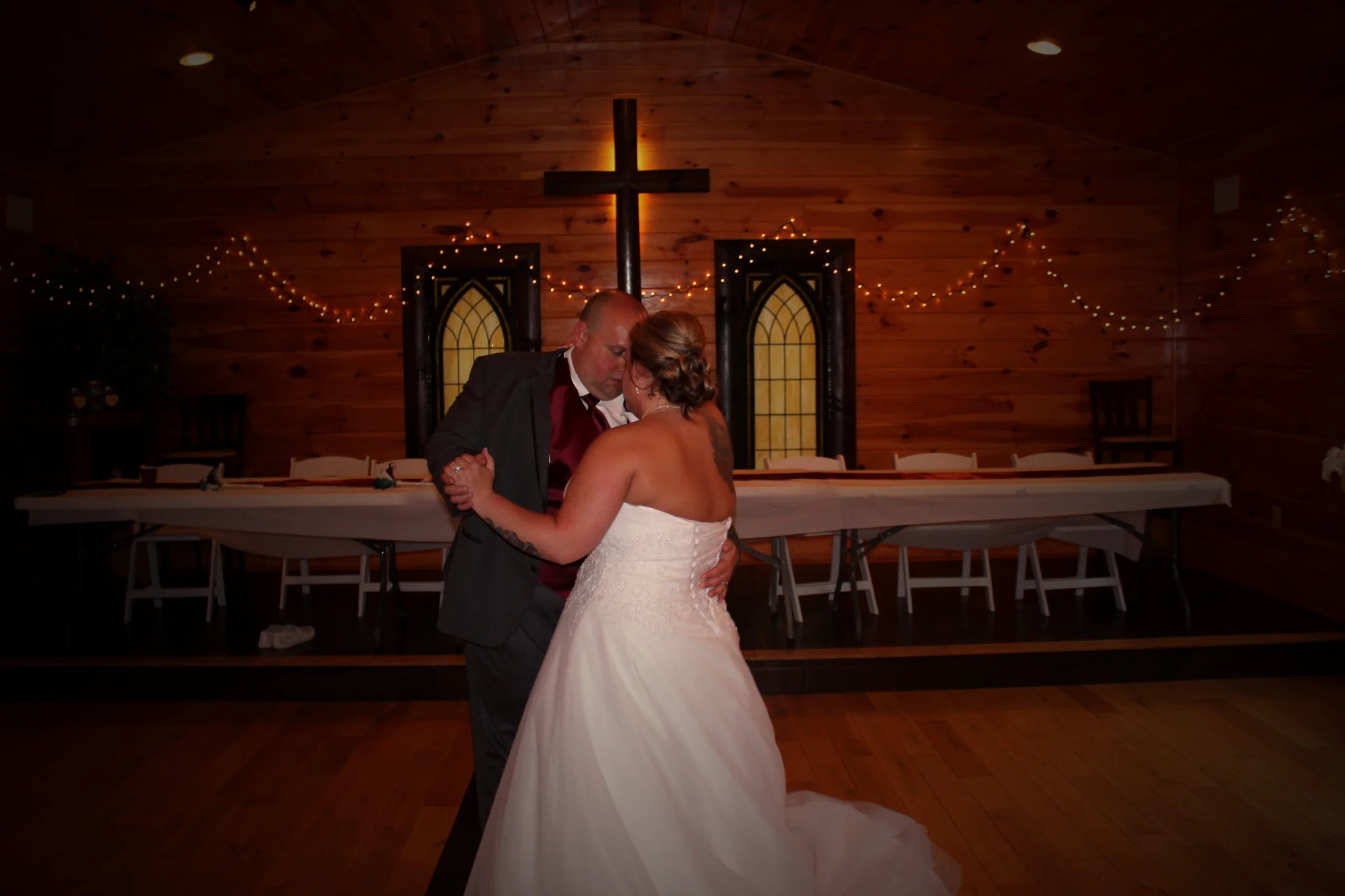 Couple dancing in a rustic wood-paneled chapel with a wooden cross at Moose Hollow Lodge in Pigeon Forge