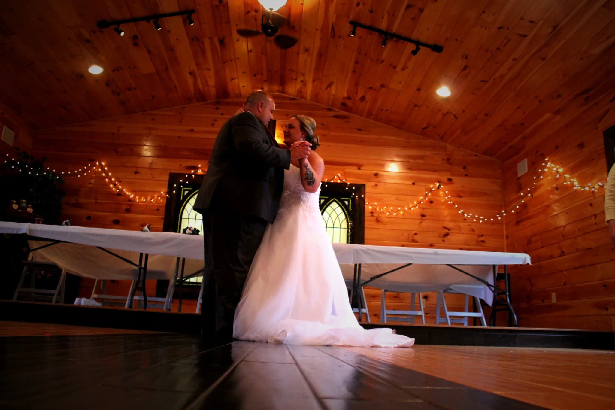 Wedding couple dancing in rustic reception hall with wood paneling at Moose Hollow Lodge in Pigeon Forge.