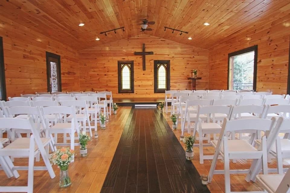 Rustic wedding chapel with wood paneling and white chairs at Moose Hollow Lodge in Pigeon Forge