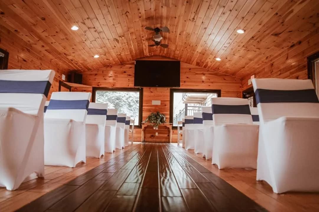 Elegant wedding ceremony seating with white chairs in a rustic wood-paneled room at Moose Hollow Lodge in Pigeon Forge