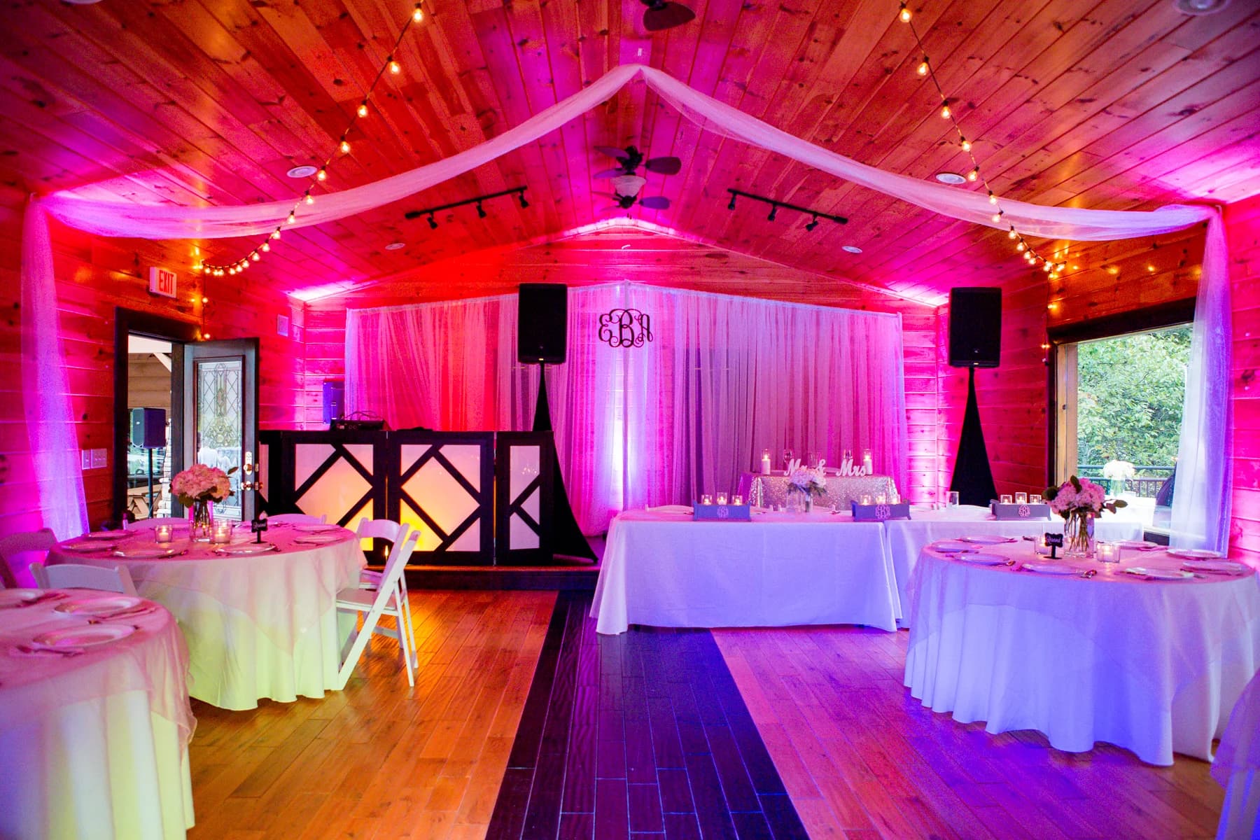 Indoor wedding reception hall with pink uplighting, tables, and drapes at Moose Hollow Lodge in Pigeon Forge