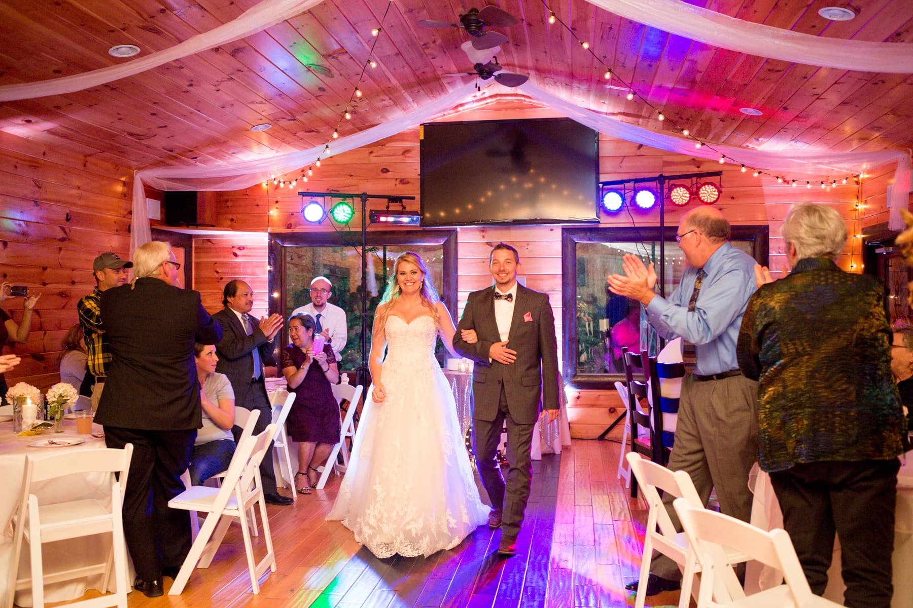 Bride and groom entering rustic wedding reception hall with string lights at Moose Hollow Lodge in Pigeon Forge