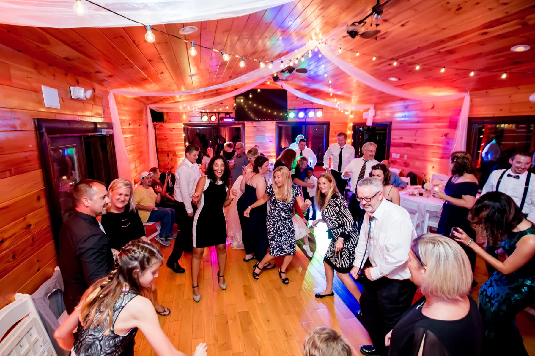 Guests dancing on a wood floor under string lights at the Moose Hollow Lodge wedding venue in Pigeon Forge