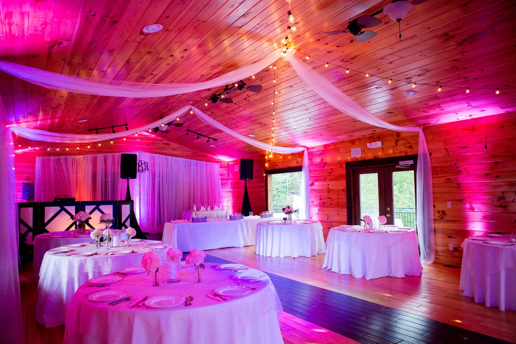 Rustic wedding reception hall with draped wood ceilings and pink lighting at Moose Hollow Lodge in Pigeon Forge