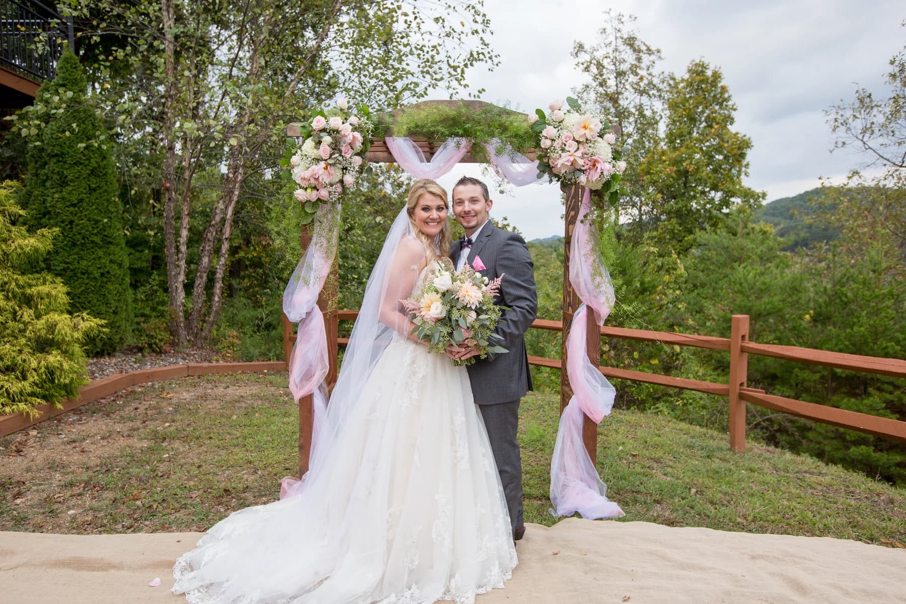 Wedding couple at outdoor floral arch with mountain views at Moose Hollow Lodge in Pigeon Forge near Dollywood
