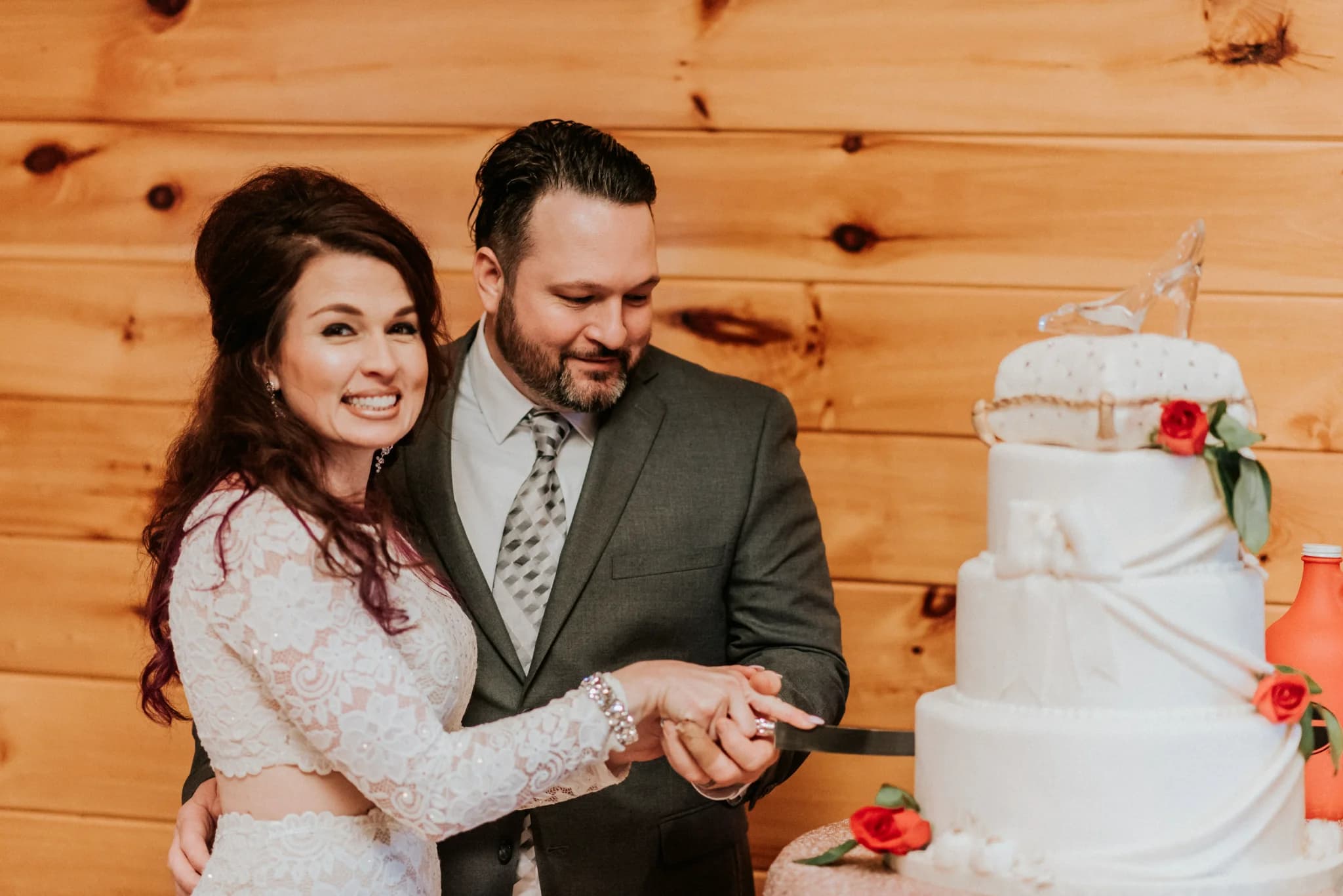 Bride and groom cutting a tiered white cake in a rustic setting at Moose Hollow Lodge in Pigeon Forge