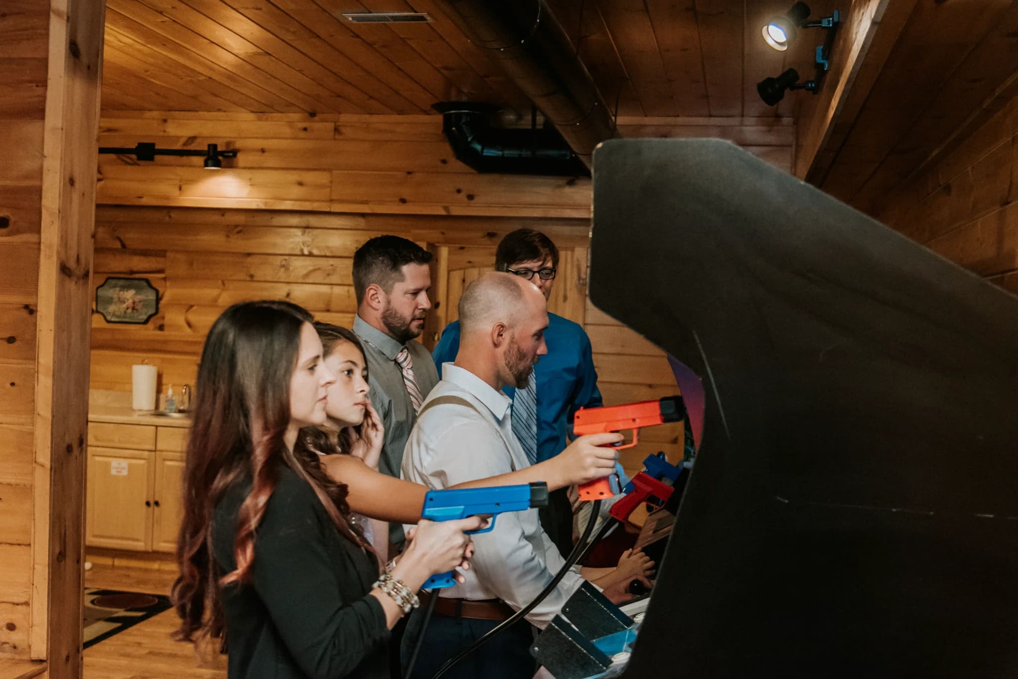 Wedding guests playing arcade shooting games in the rustic game room at Moose Hollow Lodge in Pigeon Forge