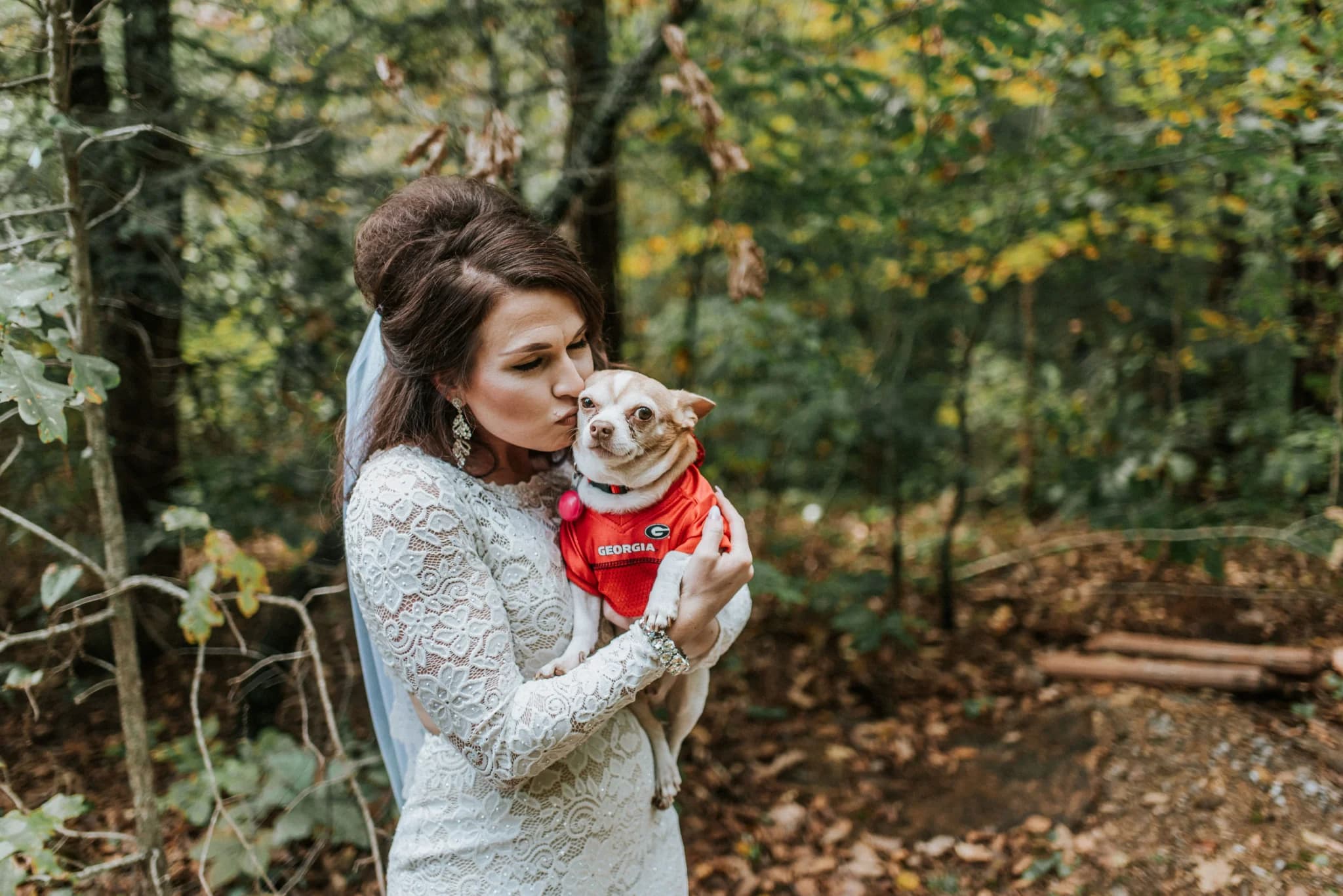 Bride in lace dress holding dog in a wooded forest at Moose Hollow Lodge in Pigeon Forge near Smoky Mountains