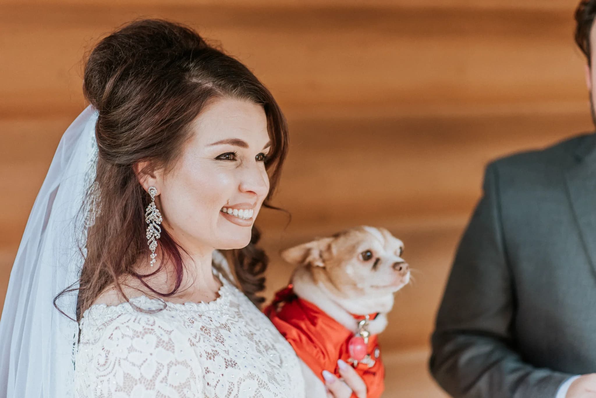 Smiling bride in lace gown holding a small dog in a rustic lodge wedding at Moose Hollow Lodge in Pigeon Forge