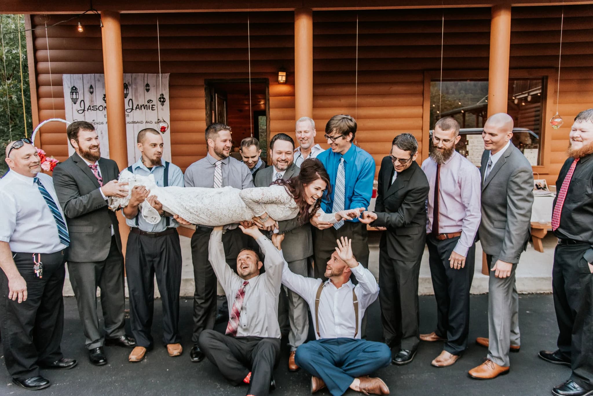 Wedding party lifting bride outside rustic log cabin at Moose Hollow Lodge in Pigeon Forge near Smoky Mountains