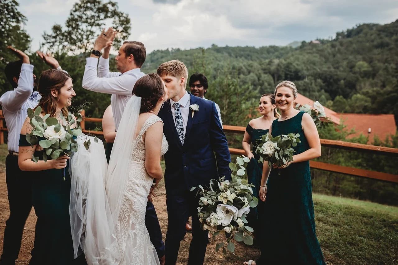 Wedding couple kissing with bridal party and Smoky Mountain views at Moose Hollow Lodge in Pigeon Forge near Dollywood.