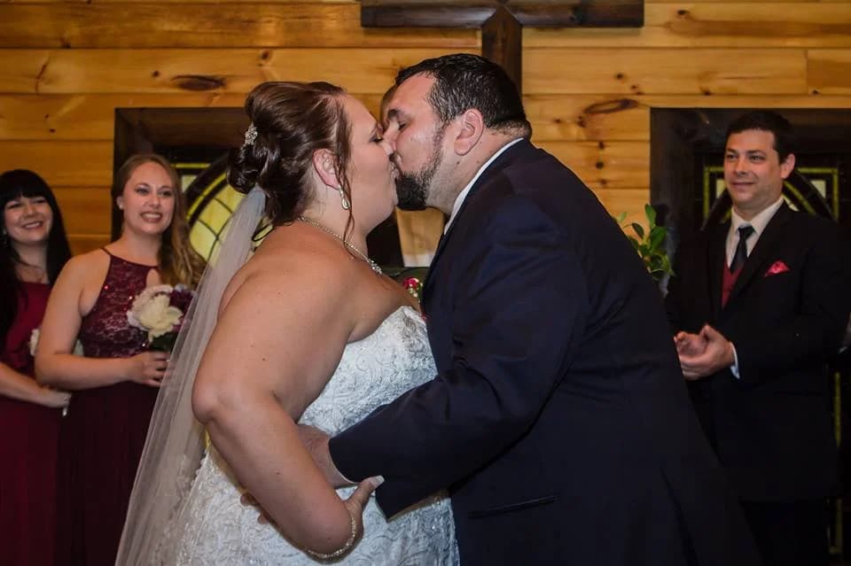 Newlyweds kiss at wedding ceremony with rustic log walls at Moose Hollow Lodge in Pigeon Forge