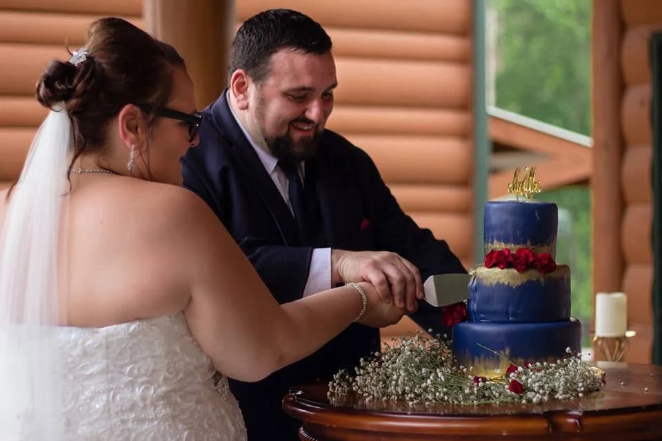 Bride and groom cutting a tiered cake in a log cabin at Moose Hollow Lodge in Pigeon Forge
