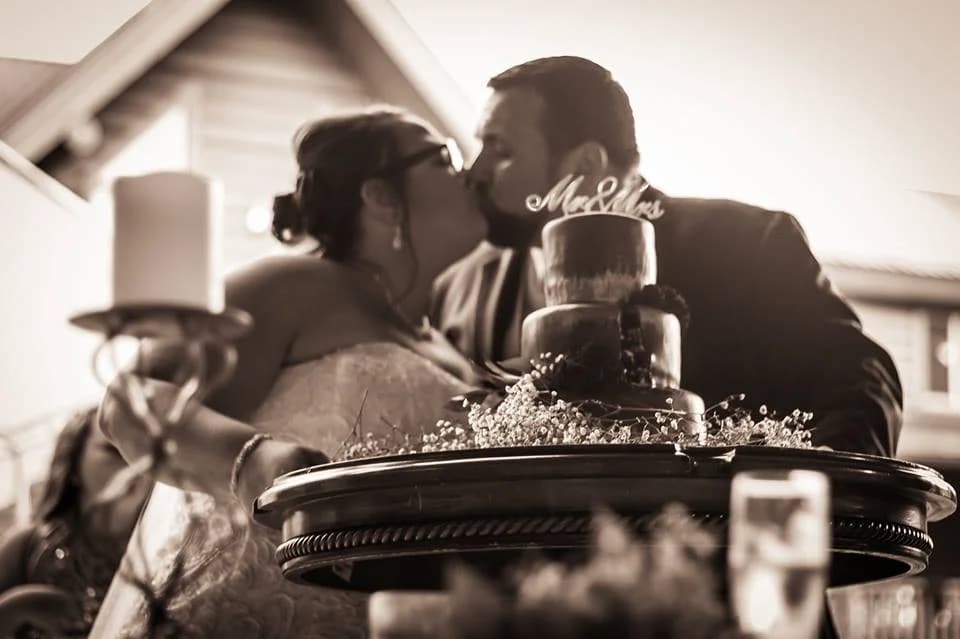 Bride and groom kissing behind a tiered wedding cake at Moose Hollow Lodge in Pigeon Forge.