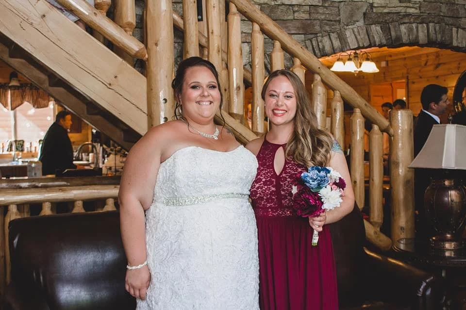 Bride and bridesmaid in rustic living room with log staircase at Moose Hollow Lodge in Pigeon Forge