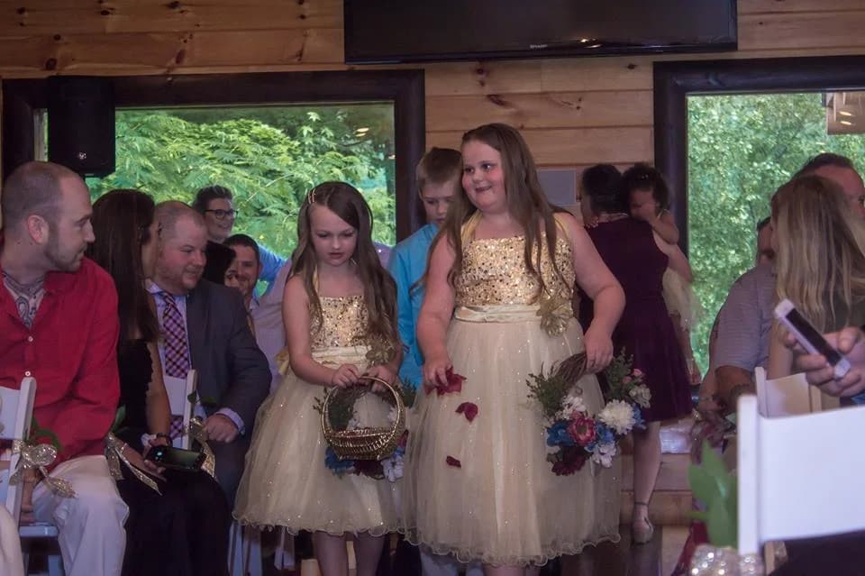 Flower girls walking down the aisle at an indoor wedding ceremony at Moose Hollow Lodge in Pigeon Forge