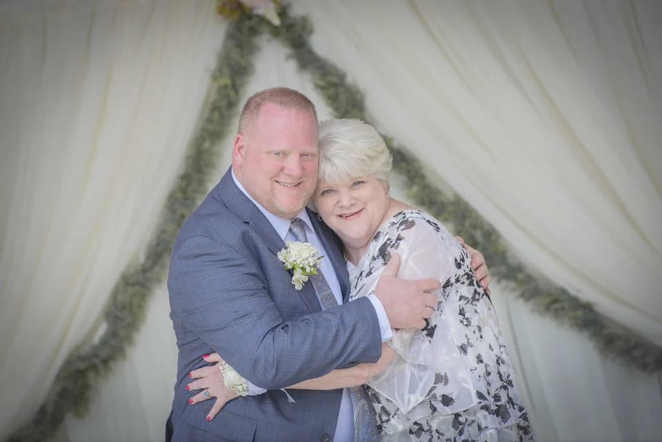 Couple hugging at indoor wedding venue with white drapes and greenery at Moose Hollow Lodge in Pigeon Forge