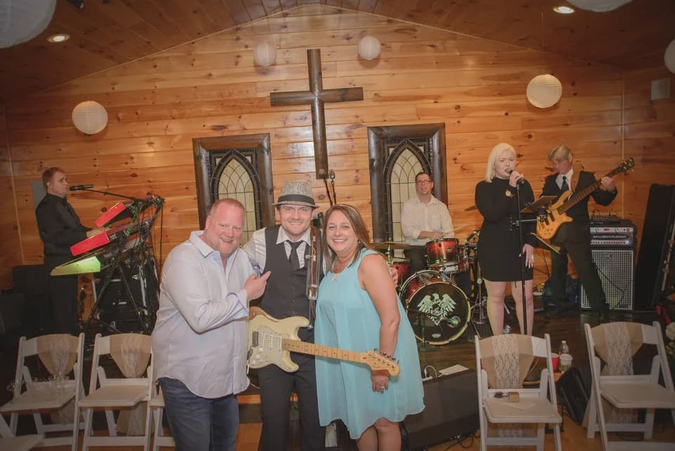 Live band performing in a rustic wood-paneled chapel with white chairs at Moose Hollow Lodge in Pigeon Forge