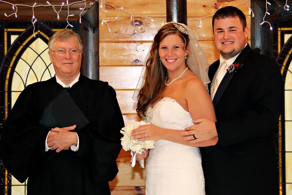 Wedding couple and officiant in a rustic log chapel with stained glass at Moose Hollow Lodge in Pigeon Forge