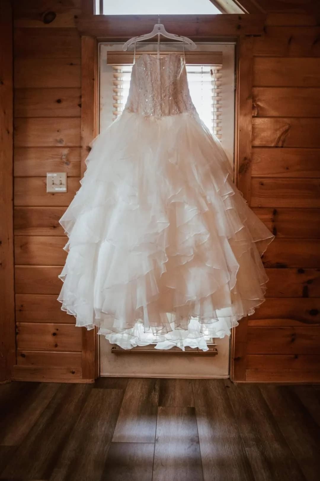White ruffled wedding dress hanging against rustic wood walls at Moose Hollow Lodge in Pigeon Forge