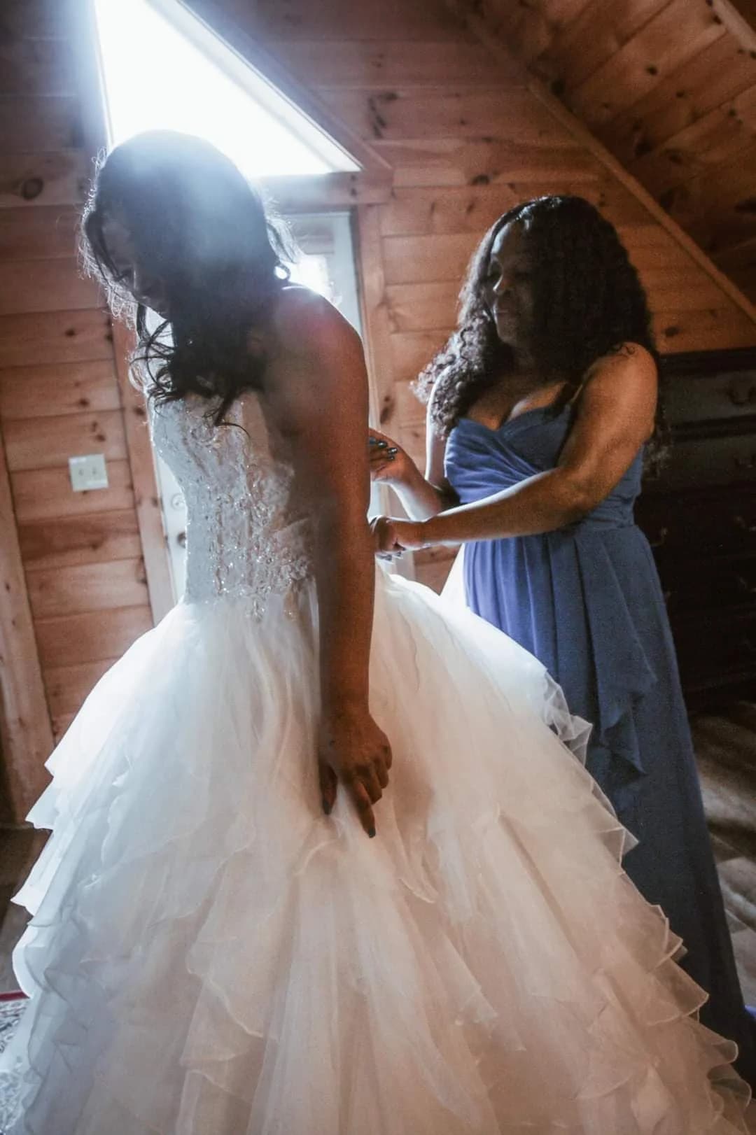 Bride in ruffled wedding gown getting ready in a wood-paneled room at Moose Hollow Lodge in Pigeon Forge.
