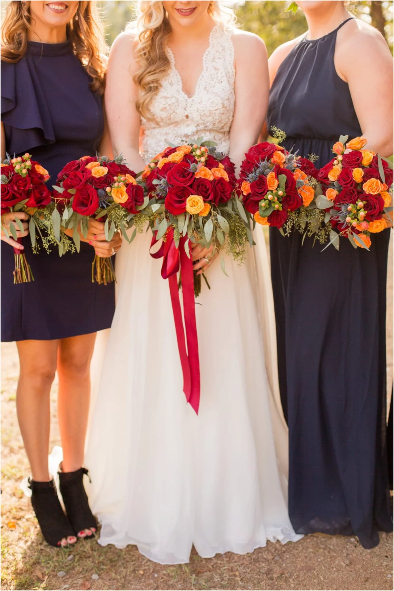 Bride and bridesmaids holding red bouquets outdoors near the Smoky Mountains at Moose Hollow Lodge in Pigeon Forge