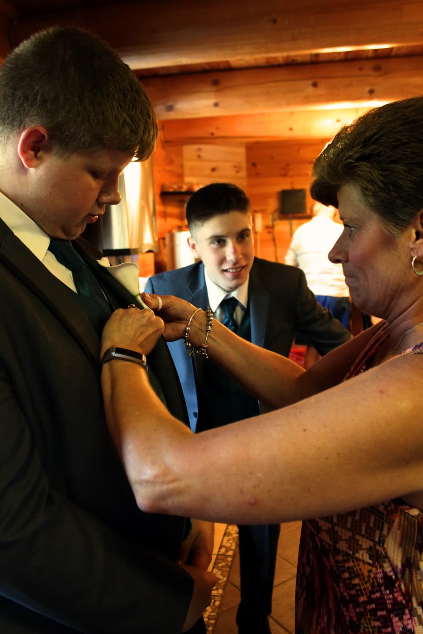 Woman pinning boutonniere on groom in a rustic log cabin interior at Moose Hollow Lodge in Pigeon Forge