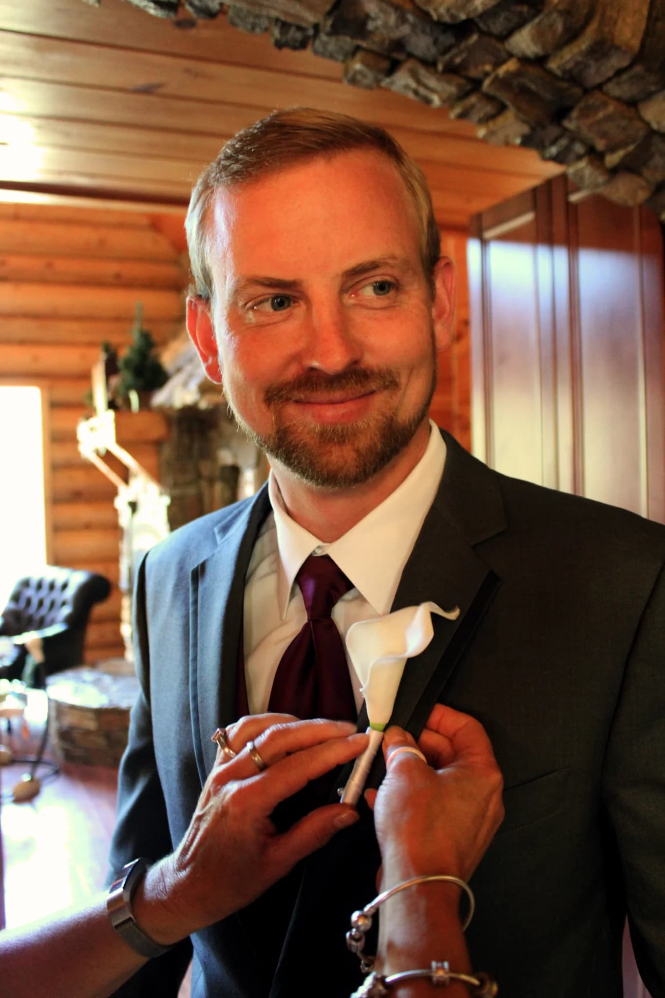 Groom pinning on a boutonniere in a rustic log cabin at Moose Hollow Lodge in Pigeon Forge