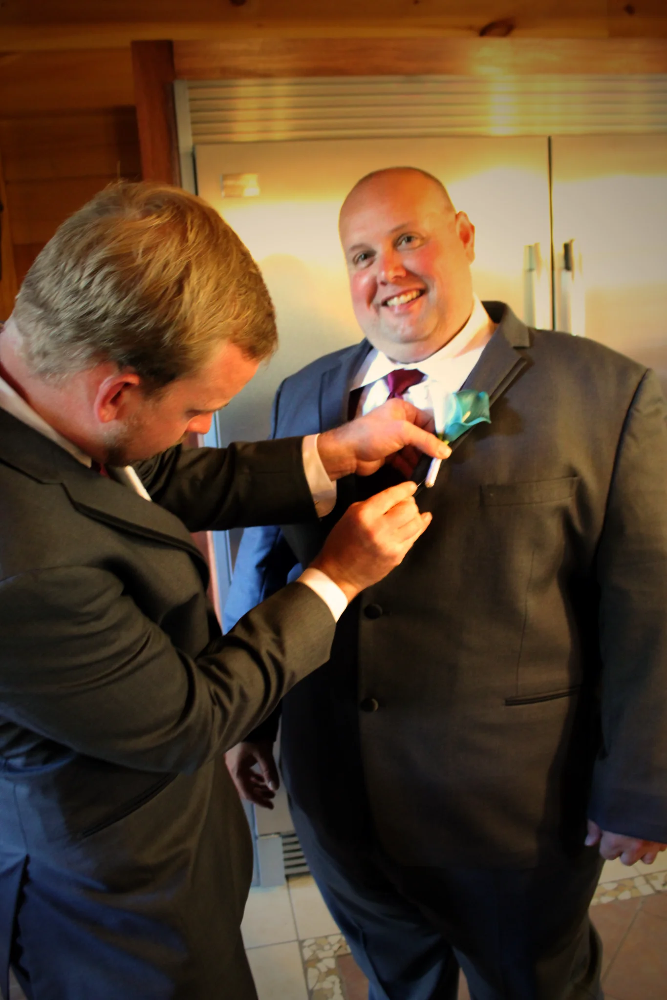 Groom getting a boutonniere pinned in the kitchen at Moose Hollow Lodge in Pigeon Forge