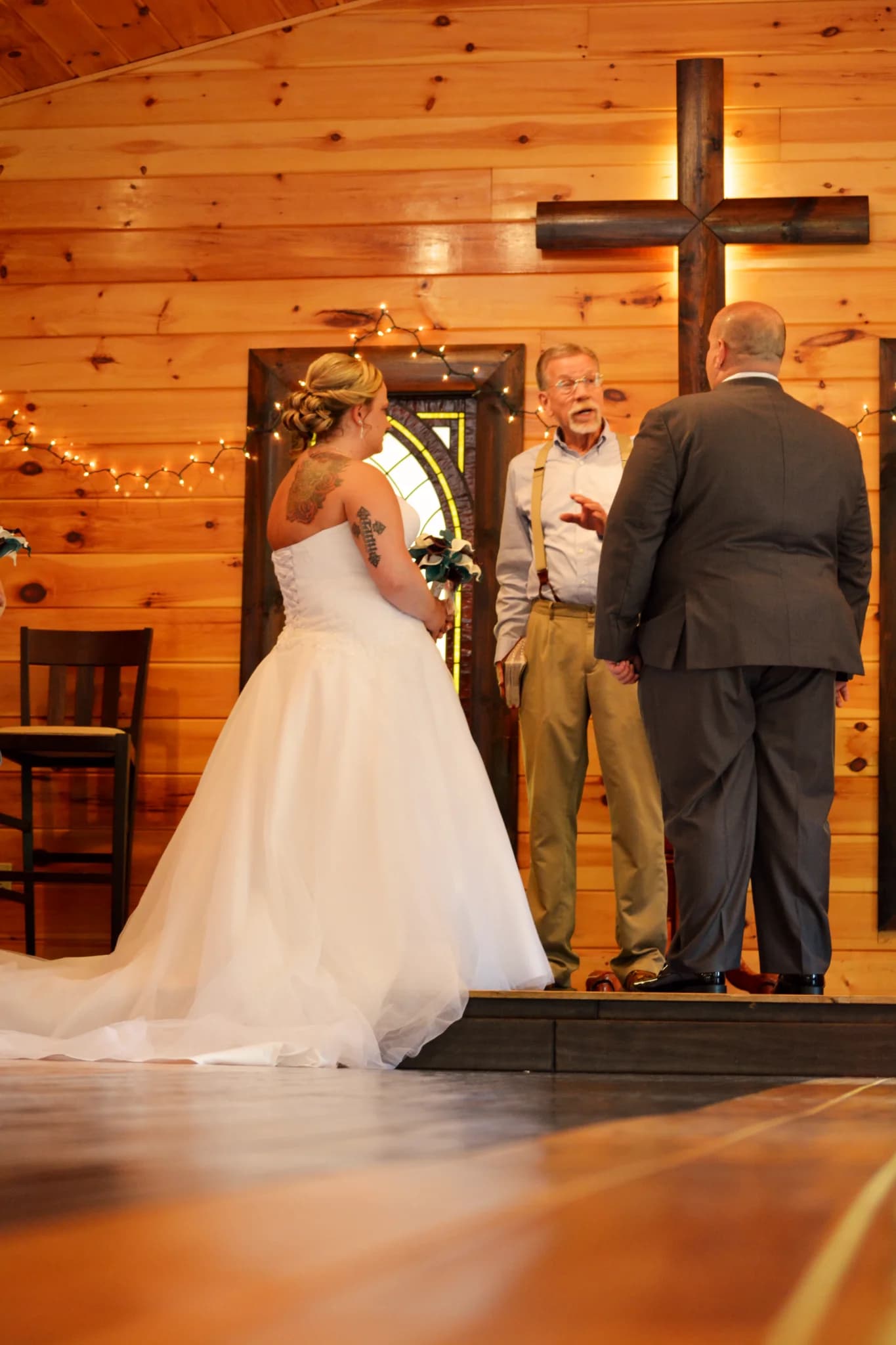 Rustic wedding ceremony in a wood-paneled chapel with a large wooden cross at Moose Hollow Lodge in Pigeon Forge
