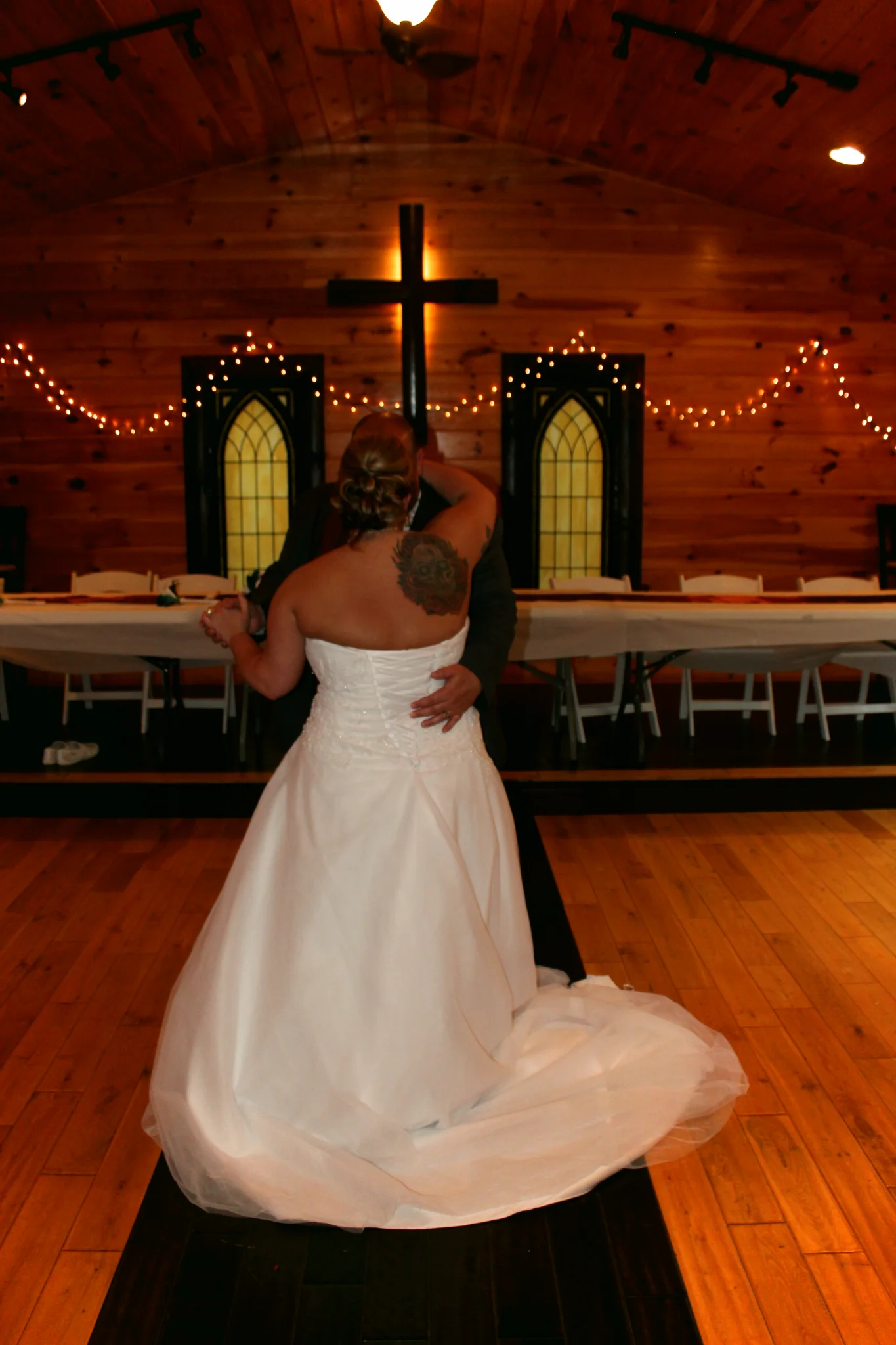Newlyweds first dance in a rustic chapel with wood walls and a cross at Moose Hollow Lodge in Pigeon Forge