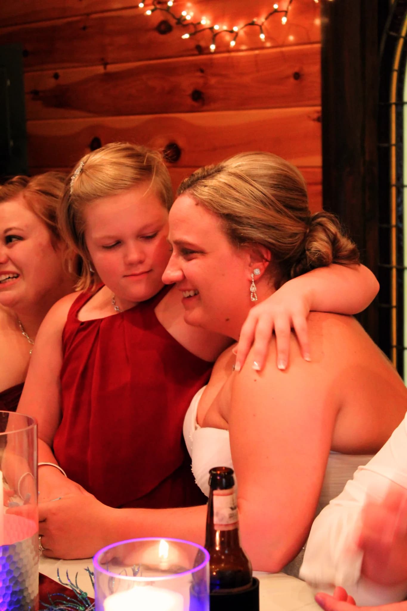 Smiling bride and flower girl hugging at rustic wedding reception at Moose Hollow Lodge in Pigeon Forge