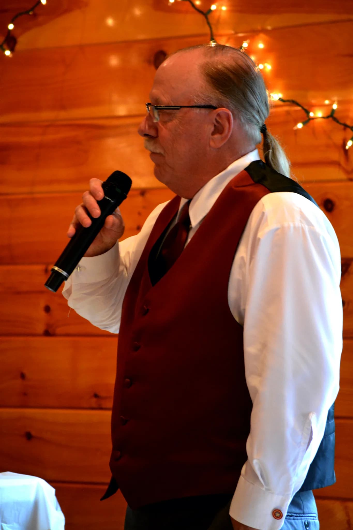 Man giving speech with microphone against rustic wood walls at Moose Hollow Lodge in Pigeon Forge