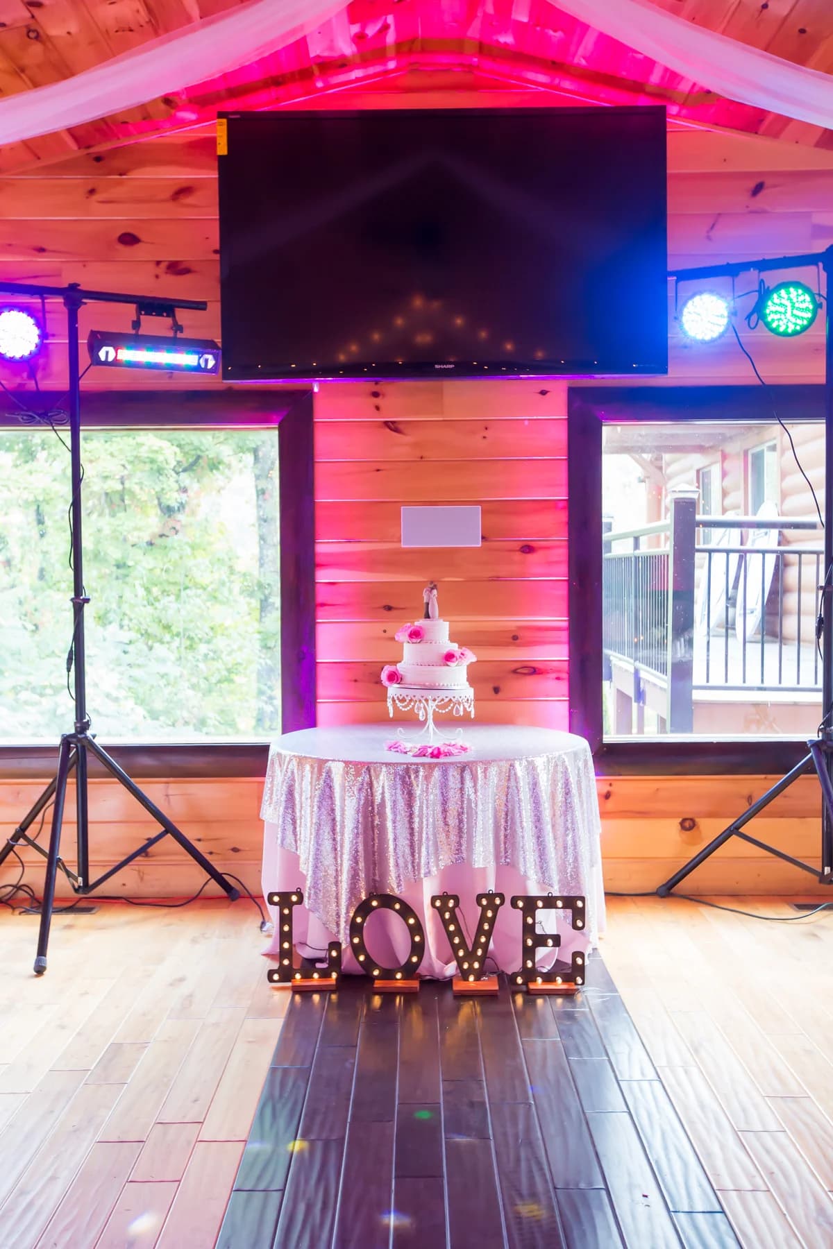 Tiered wedding cake on sequin table with LOVE sign and event lighting at Moose Hollow Lodge in Pigeon Forge