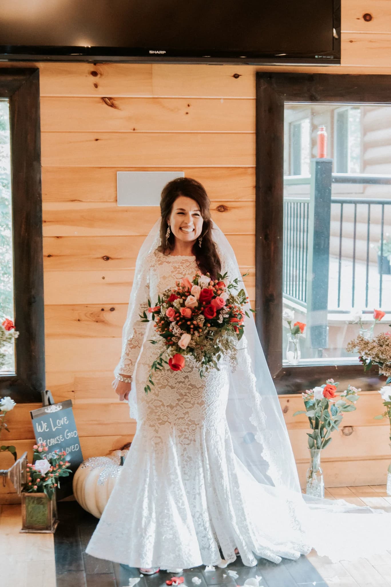 Bride in lace gown with rose bouquet inside rustic log wedding venue at Moose Hollow Lodge in Pigeon Forge