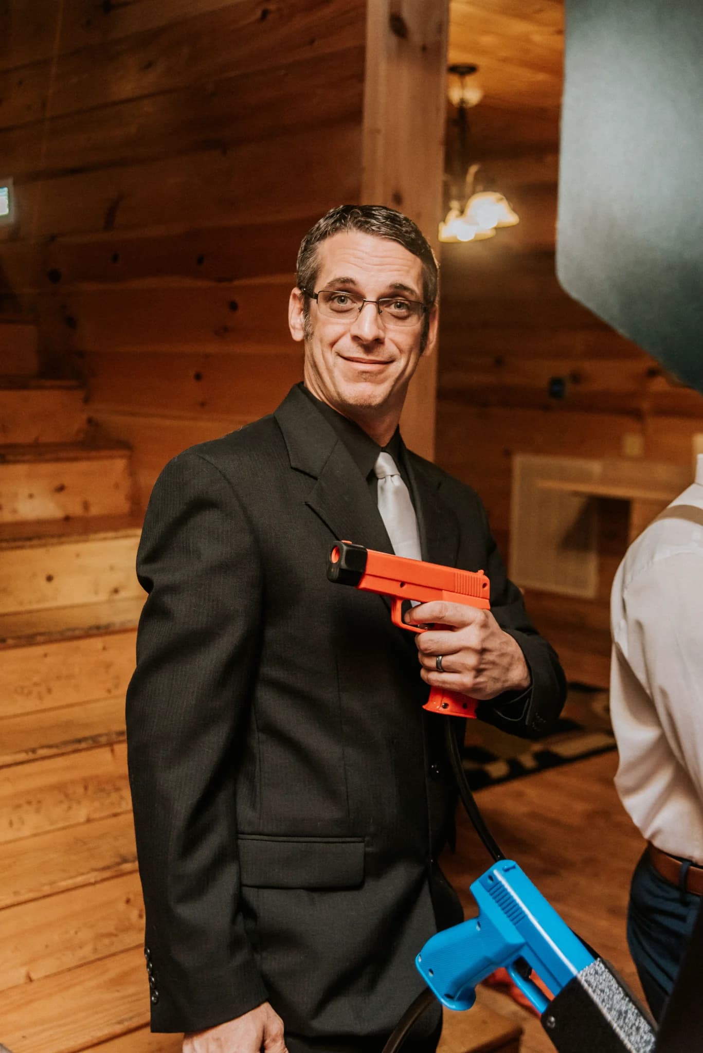 Man in suit with arcade gun in the rustic game room at Moose Hollow Lodge in Pigeon Forge