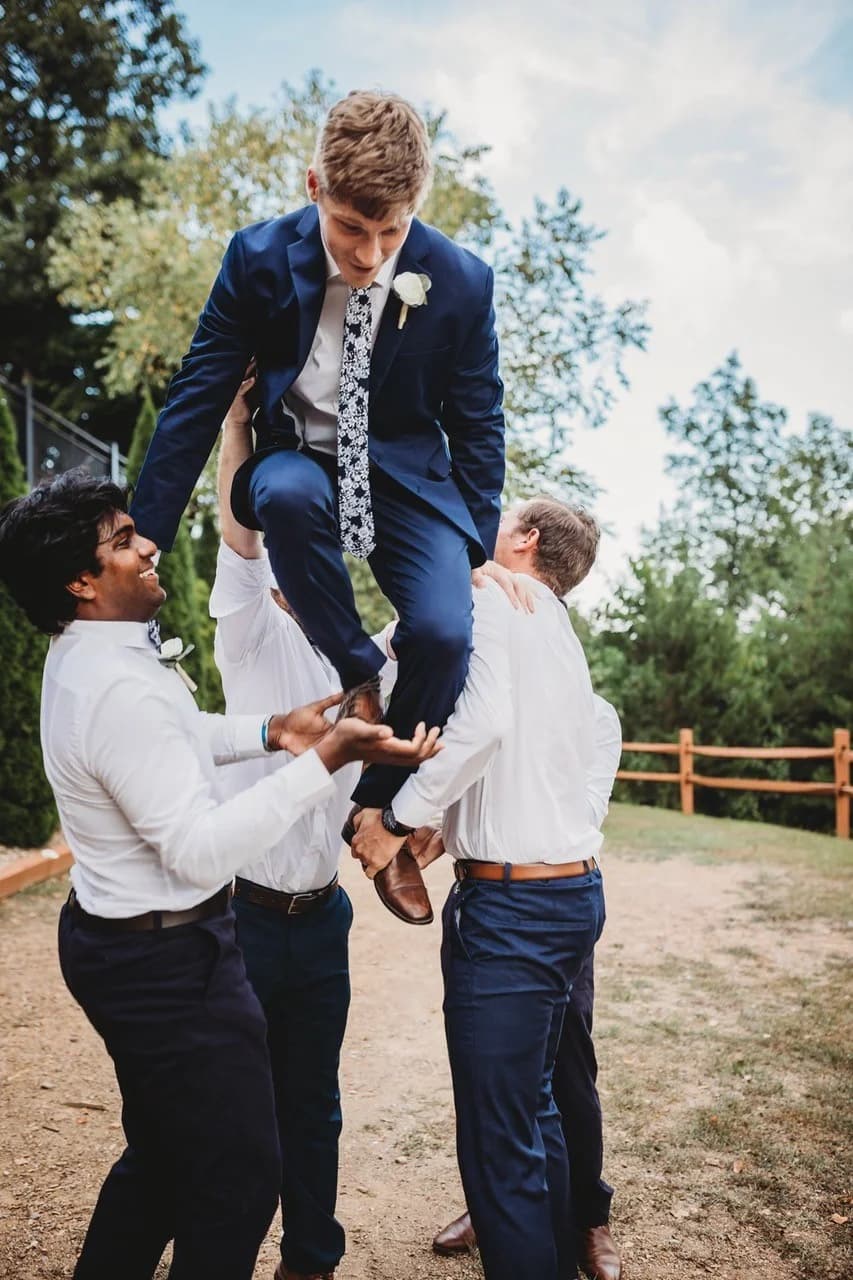 Groomsmen lifting groom during outdoor wedding celebration at Moose Hollow Lodge in Pigeon Forge near the Smoky Mountains