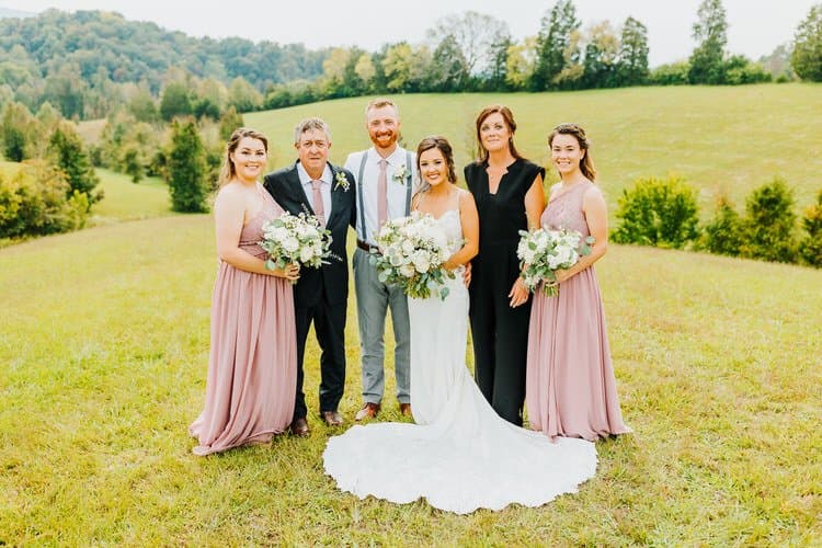 Wedding group portrait outdoors at Moose Hollow Lodge, Sevierville. Bride, groom, and family stand in grassy field.