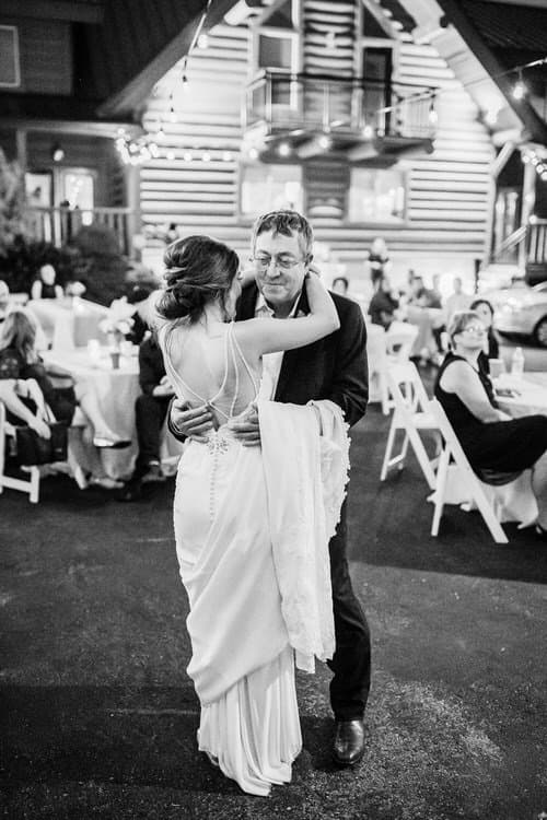 Bride and man dancing outdoors at night at Moose Hollow Lodge, with string lights and guests seated at tables.