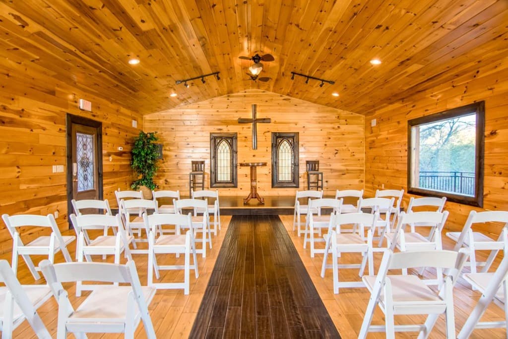 Wood-paneled wedding chapel with rows of white chairs and altar cross at Moose Hollow Lodge in Sevierville, TN